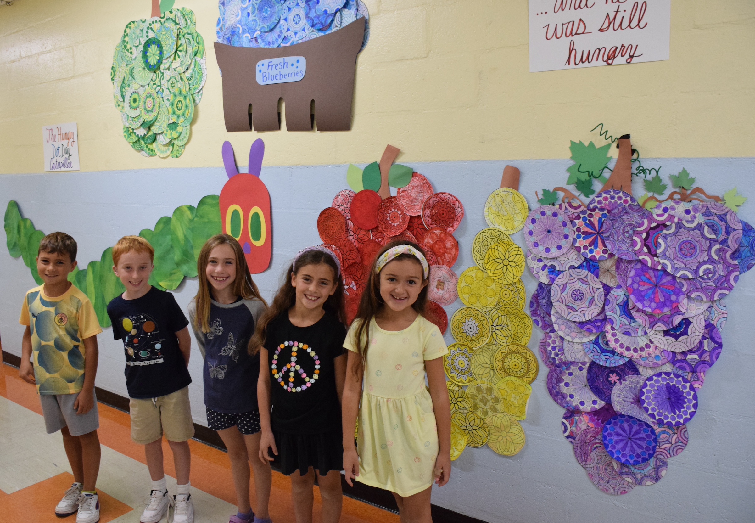kids posing in front of art work on the wall